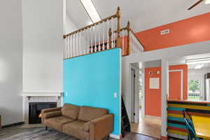 Living room featuring a high ceiling, ceiling fan, wood finished floors, and a tile fireplace