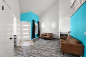 Entrance foyer with high vaulted ceiling, wood finished floors, and a tile fireplace