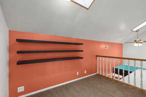 Carpeted empty room with vaulted ceiling and ceiling fan