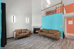 Living room with a towering ceiling, wood finished floors, and a tiled fireplace