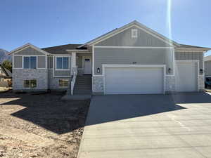 Craftsman inspired home with board and batten siding, driveway, an attached garage, and stone siding