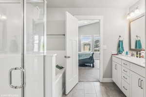 Ensuite bathroom featuring double vanity, a garden tub, a stall shower, and tile patterned flooring