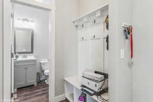 Mudroom with dark wood finished floors and a sink