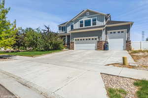 View of front of property featuring board and batten siding, stone siding, driveway, and a garage