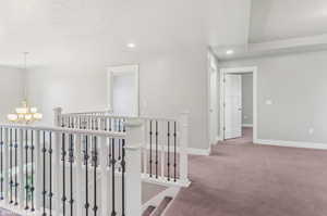 Hall featuring a chandelier, carpet, recessed lighting, and an upstairs landing