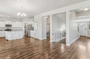 Kitchen with appliances with stainless steel finishes, dark wood finished floors, a kitchen bar, white cabinetry, and recessed lighting