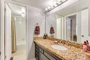 Bathroom featuring vanity, shower / bath combo, and tile patterned floors