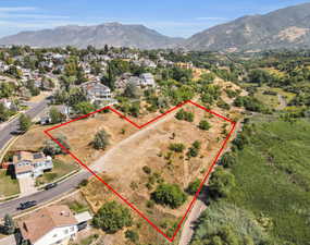 Aerial view of residential area with property parcel outlined and mountains