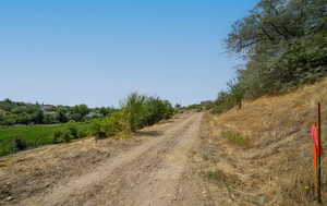View of dirt / gravel road featuring a view of rural / pastoral area