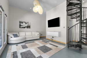 Lower level Living room featuring spiral stairway and finished concrete flooring