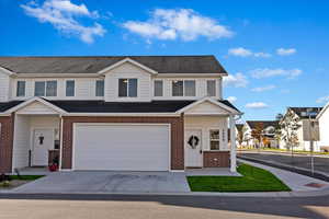 View of property featuring brick siding, concrete driveway, an attached garage, and roof with shingles