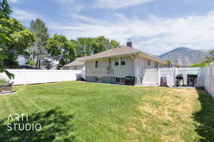 Back of house with a fenced backyard, a gate, a chimney, and a mountain view