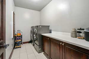 Washroom with cabinet space, separate washer and dryer, and light tile patterned flooring