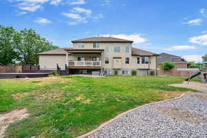 Rear view of house with stucco siding, a playground, a garden, and a wooden deck