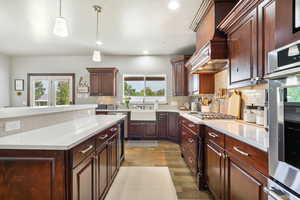 Kitchen featuring decorative backsplash, light countertops, light wood-style flooring, recessed lighting, and custom range hood