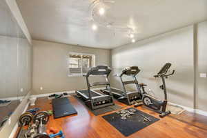 Exercise area featuring wood finished floors and track lighting