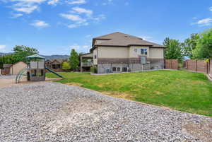 Back of house with brick siding, stucco siding, a playground, roof with shingles, and a mountain view