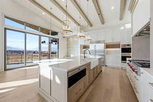 Kitchen with hanging light fixtures, a mountain view, white cabinets, light wood finished floors, and recessed lighting