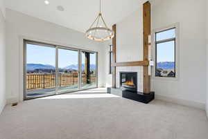 Unfurnished living room featuring a mountain view, carpet, a fireplace, and high vaulted ceiling