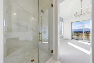Full bath featuring a marble finish shower, a mountain view, carpet floors, lofted ceiling, and a chandelier