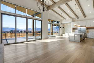 Living area featuring a chandelier, a mountain view, high vaulted ceiling, light wood-type flooring, and beamed ceiling