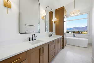 Full bathroom with double vanity, a soaking tub, and a mountain view