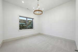 Carpeted empty room featuring a chandelier and recessed lighting