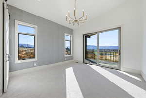 Spare room with a mountain view, healthy amount of natural light, lofted ceiling, and a chandelier