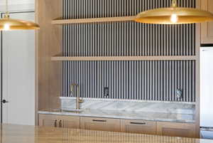 Detailed view of freestanding refrigerator, light stone countertops, and pendant lighting