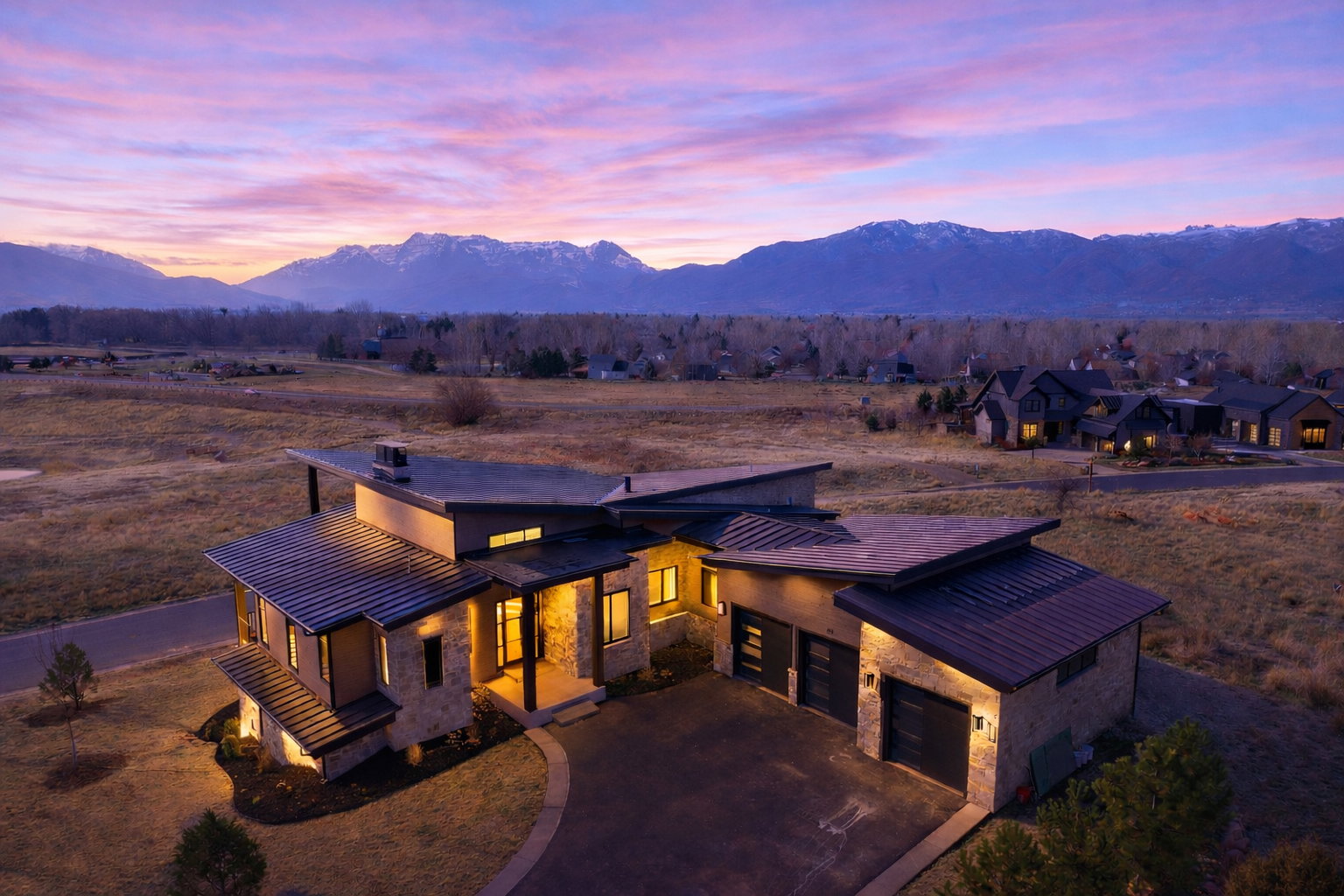 View of front of home with stone siding, a standing seam roof, a mountain view, asphalt driveway, and an attached garage