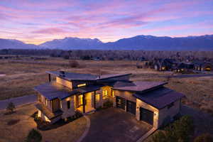 View of front of home with stone siding, a standing seam roof, a mountain view, asphalt driveway, and an attached garage