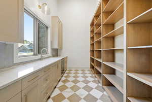 Bar area with light flooring, light stone counters, and wine cooler