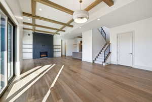 Unfurnished living room featuring beam ceiling, coffered ceiling, stairway, recessed lighting, and wood finished floors