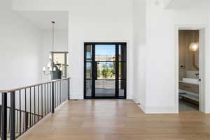 Foyer featuring light wood-type flooring, a chandelier, and a high ceiling