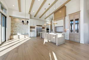 Kitchen featuring a chandelier, a kitchen bar, decorative light fixtures, a spacious island, and a towering ceiling