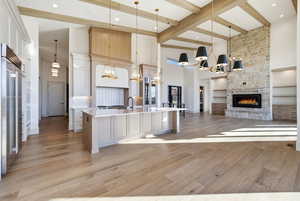 Kitchen featuring a chandelier, open floor plan, decorative light fixtures, a towering ceiling, and a large island with sink