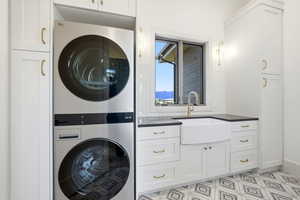 Laundry area with stacked washer / drying machine, light floors, cabinet space, and a mountain view