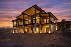 Back of house featuring stone siding, a patio area, and a balcony