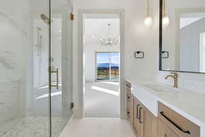 Full bath featuring light colored carpet, vanity, a marble finish shower, a mountain view, and a chandelier