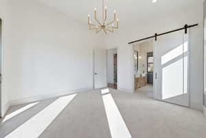 Unfurnished dining area with a barn door, a chandelier, and light carpet