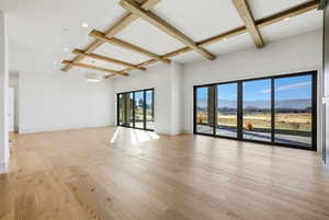 Spare room with coffered ceiling, beamed ceiling, a mountain view, light wood-style floors, and recessed lighting