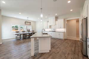 Kitchen featuring freestanding refrigerator, decorative backsplash, wood finished floors, white cabinets, and recessed lighting
