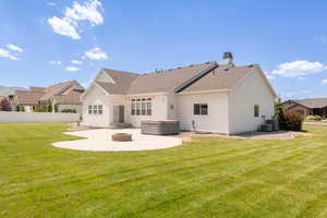 Rear view of property with a patio area, a hot tub, roof with shingles, a chimney, and an outdoor fire pit