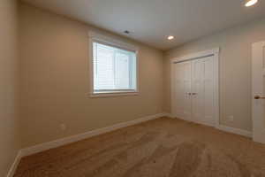 Unfurnished bedroom featuring recessed lighting, light carpet, and a closet