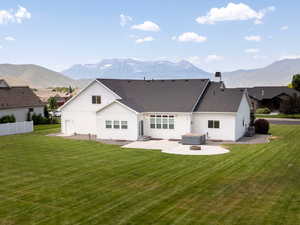 Back of house featuring a patio, a mountain view, a hot tub, and a chimney