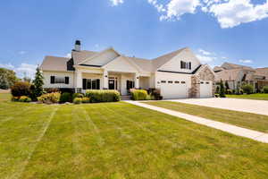 View of front of property featuring driveway, a chimney, a garage, and a front yard