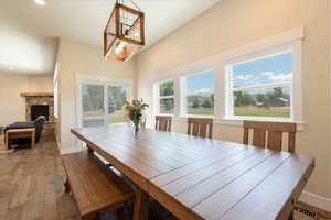 Dining area with hardwood / wood-style floors, recessed lighting, and a stone fireplace