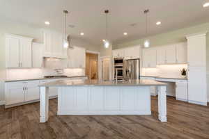 Kitchen featuring appliances with stainless steel finishes, white cabinets, decorative backsplash, and recessed lighting