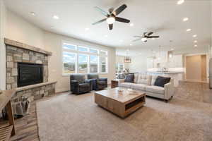 Living room with a ceiling fan, recessed lighting, light wood-type flooring, and a stone fireplace