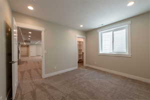 Unfurnished bedroom with light colored carpet, recessed lighting, a spacious closet, and a textured ceiling